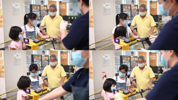 一名亚洲华人老人周末和他的孙女一起结帐和买杂货