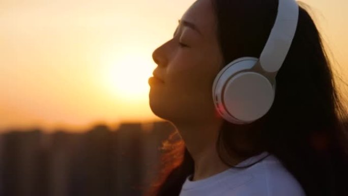 戴着耳机的女孩在日落时听音乐