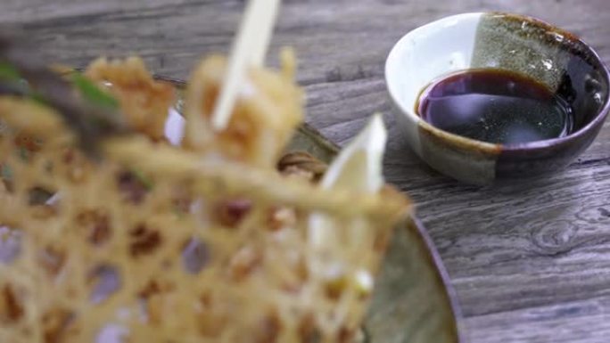 筷子拿起油炸鱿鱼油条，蘸酱。