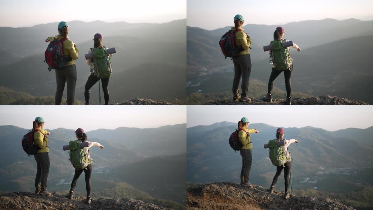 两个带着野营背包的女徒步旅行者步行和徒步到山顶