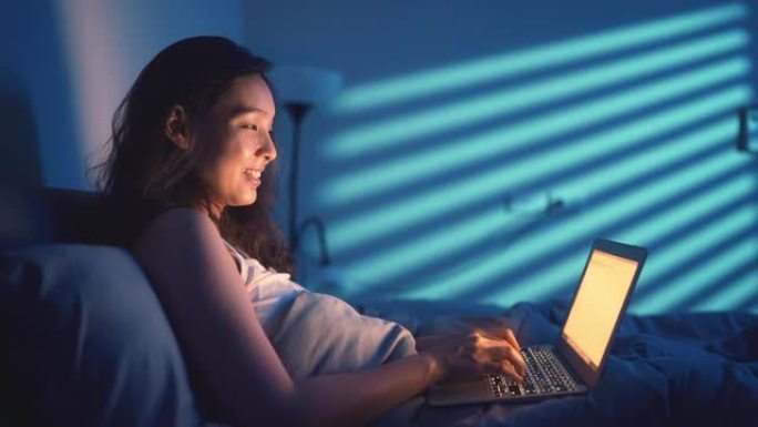 女人晚上在床上使用笔记本电脑