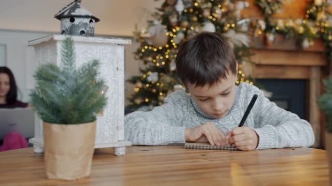 小男孩在寒假前用笔记本电脑给父母写信给圣诞老人