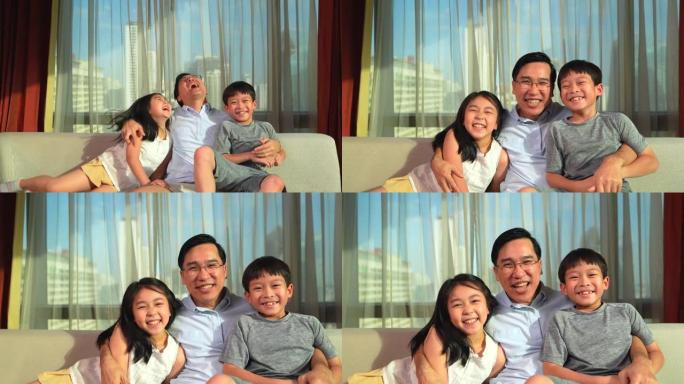 一位父亲和两个孩子，女儿和他们的儿子坐在一起，看着相机热情地拥抱在一起。传达家庭的爱。温暖的家庭是宜