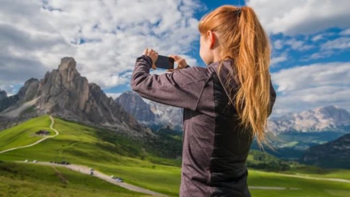 在草地上拍摄山景的女旅行者