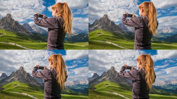 在草地上拍摄山景的女旅行者