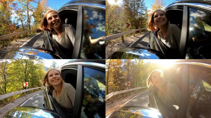 一个快乐的年轻女子在秋天的公路旅行中从车窗里倾斜的镜头