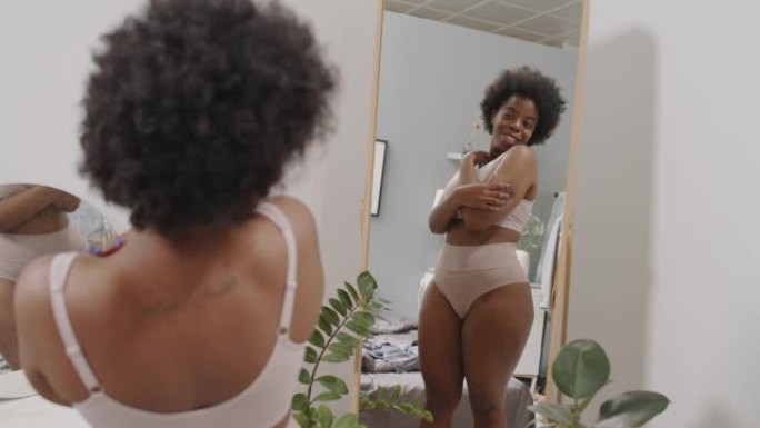 弯曲的黑人妇女享受镜子中的倒影