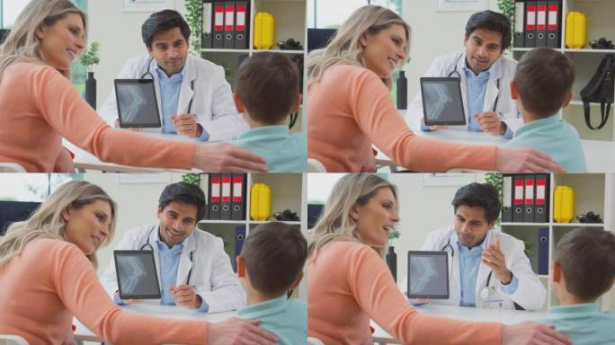 穿着白大褂的医生或全科医生会见母子预约看数字平板电脑的扫描-慢动作拍摄