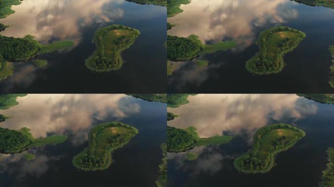 生态学概念。无人机在令人难以置信的静止湖上的小岛上方高高飞行，反射着白俄罗斯的云彩和天空。