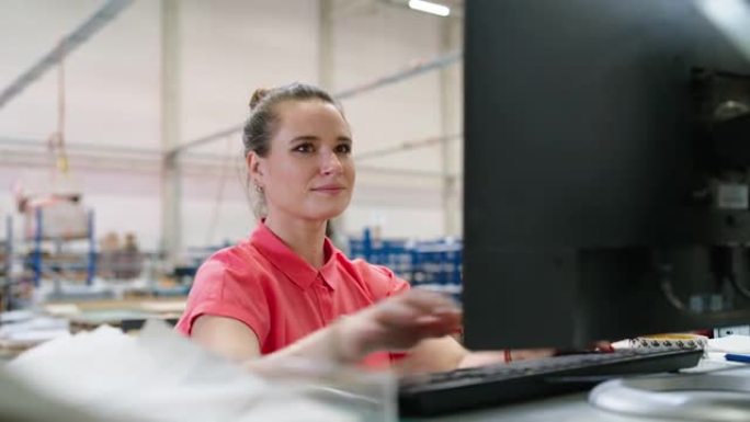 在工厂仓库用电脑工作的快乐年轻女工