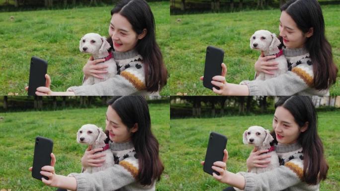 中国妇女与狗在智能手机上自拍。