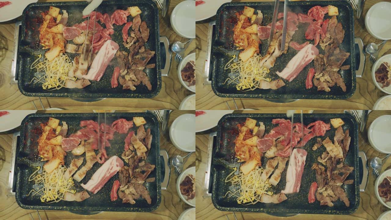 使用钳子的人的特写镜头在热锅中烧烤切成薄片的牛肉。