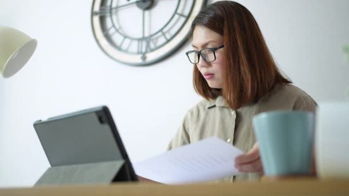 女人在家工作，分析图形和使用数字平板电脑