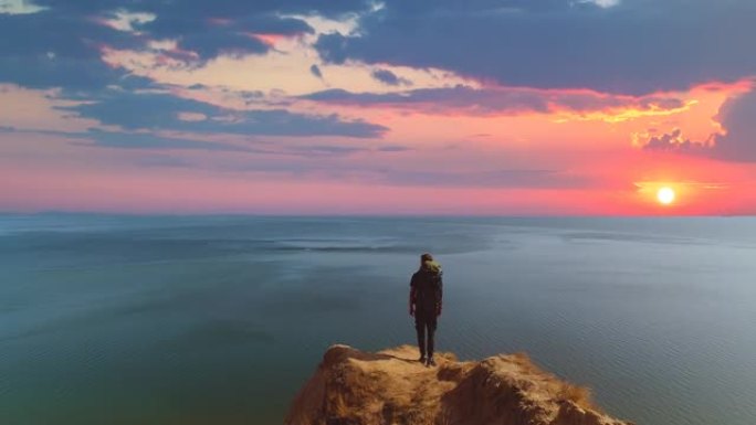 带袋子的人站在海景的山崖上背景