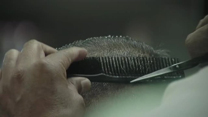 男性发型师服务客户，用剪刀理发。特写。