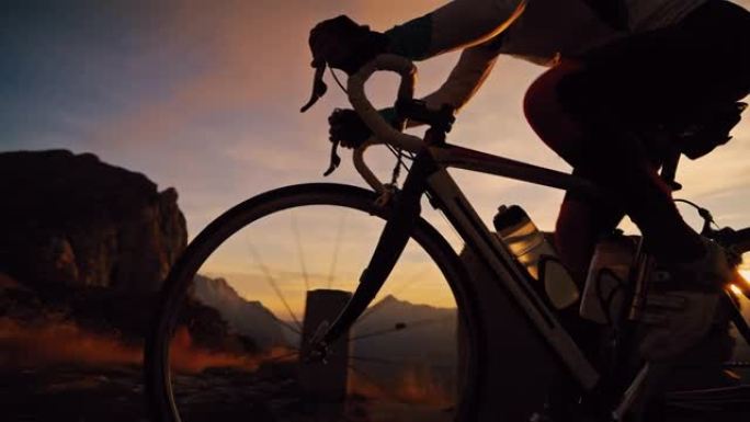骑自行车的人在日出时在山路上坡骑自行车
