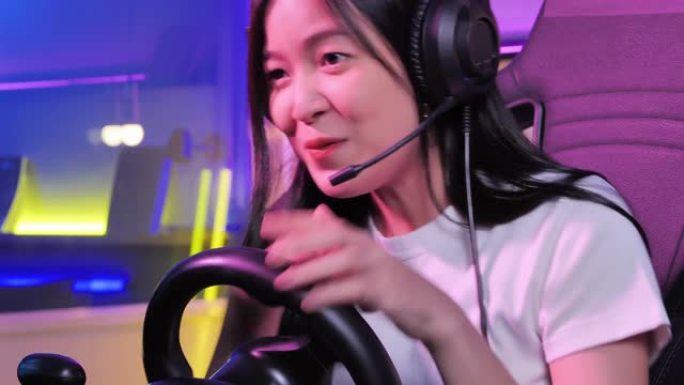 激动的千禧一代和Z世代的亚洲少女在夜间在彩色紫外线照明客厅玩赛车在线视频游戏时使用电脑pc，呆在家里