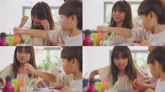 亚洲父亲与孩子们在家里的桌子上做手艺玩得开心