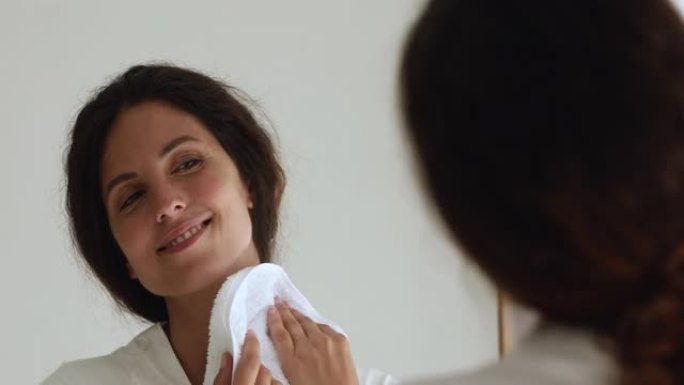 女人在用柔软的毛巾擦脸时照镜子