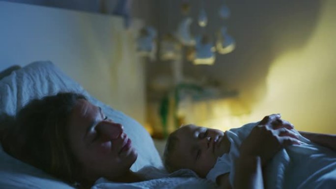 一个年轻的和平的neo母亲的真实电影镜头正在晚上与她刚出生的男婴在托儿所的床上睡觉。