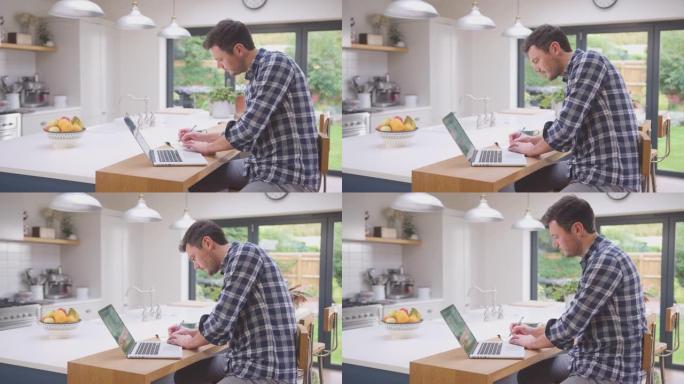 男子在家工作，在厨房柜台上使用笔记本电脑