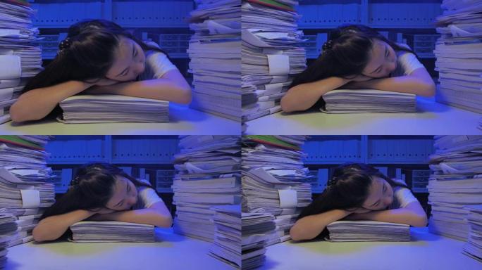 亚洲年轻女性在深夜工作的办公桌上睡觉时过度劳累。新型冠状病毒肺炎在家工作。