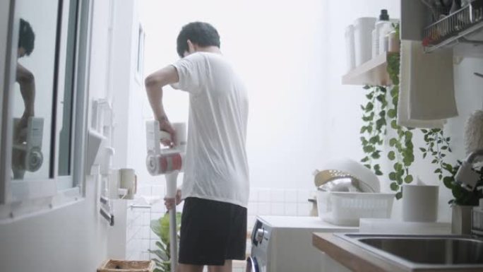时髦的亚洲男子用吸尘器清洁