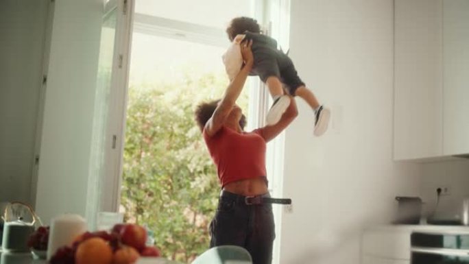 快乐的母亲抱着可爱的男婴，在现代家庭客厅玩耍，玩耍。非洲妇女举起并将蹒跚学步的孩子扔向空中。童年、新