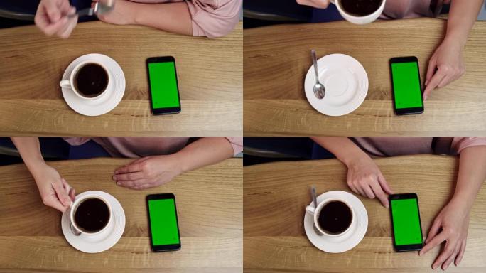 女士无法辨认的女人在家里喝咖啡时使用带有色度键绿屏的智能手机