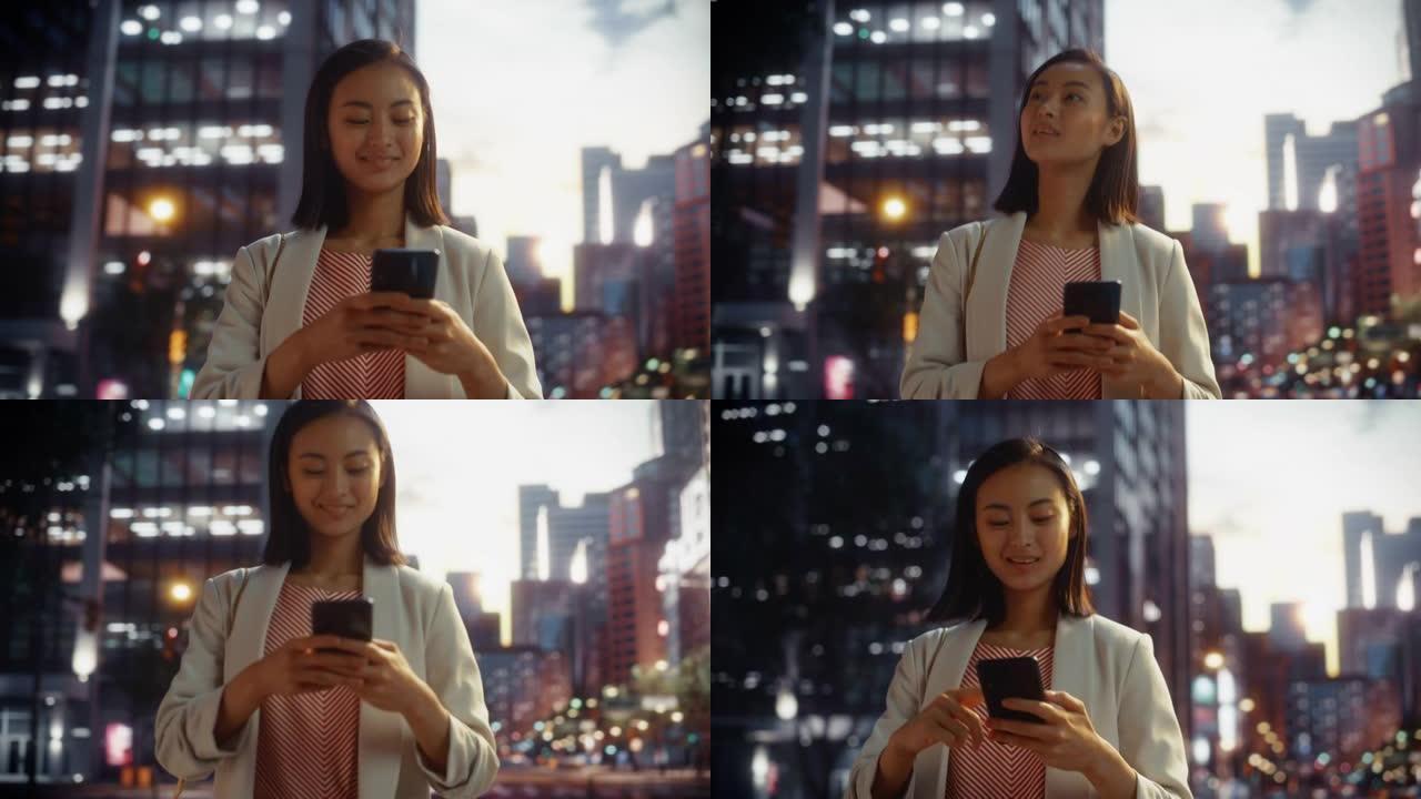 一位美丽的日本女性在日落时穿着时髦的休闲服行走并使用智能手机的肖像。时尚的女人在网上与人联系，传递信