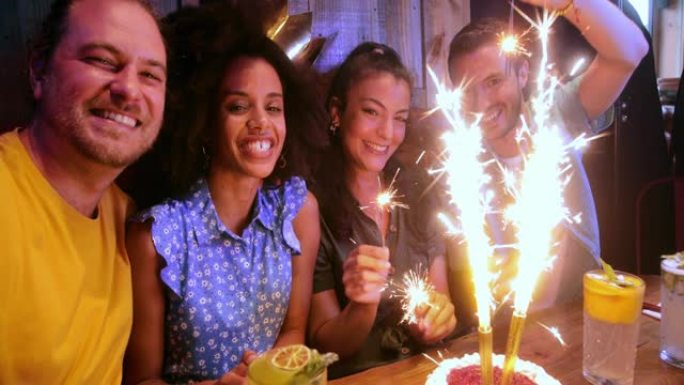 庆祝生日的朋友在餐厅里拿着火花自拍