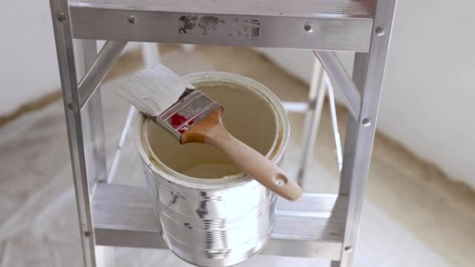 用油漆刷关闭梯子上的油漆罐