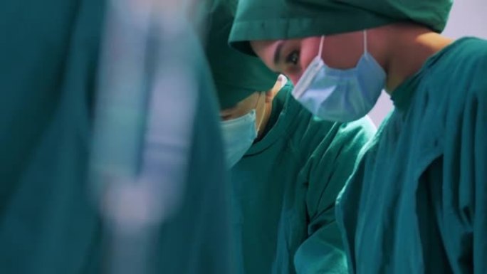 亚洲女性医生外科专业人员的特写镜头，医生团队穿着手术服，而头脑风暴力量在医院协助手术。医疗团队进行外