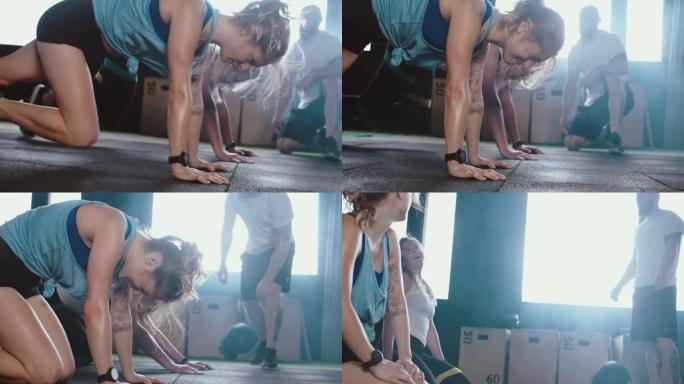 特写两名年轻快乐的白人女性在男教练的指导下在健身房地板上做腿部锻炼，给高五累。