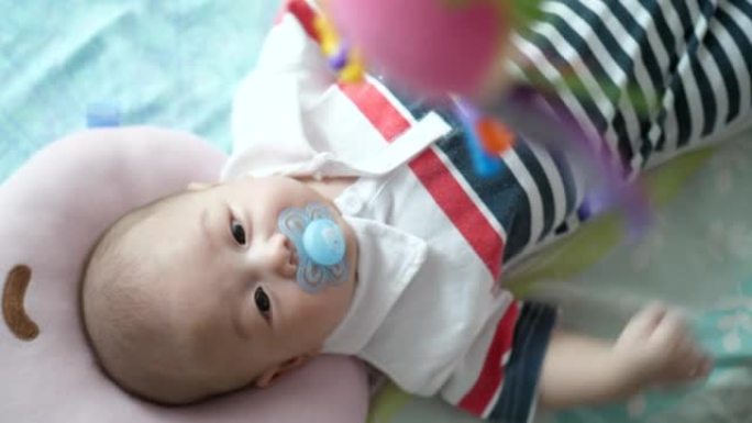可爱的婴儿躺在婴儿床里看着悬挂的玩具