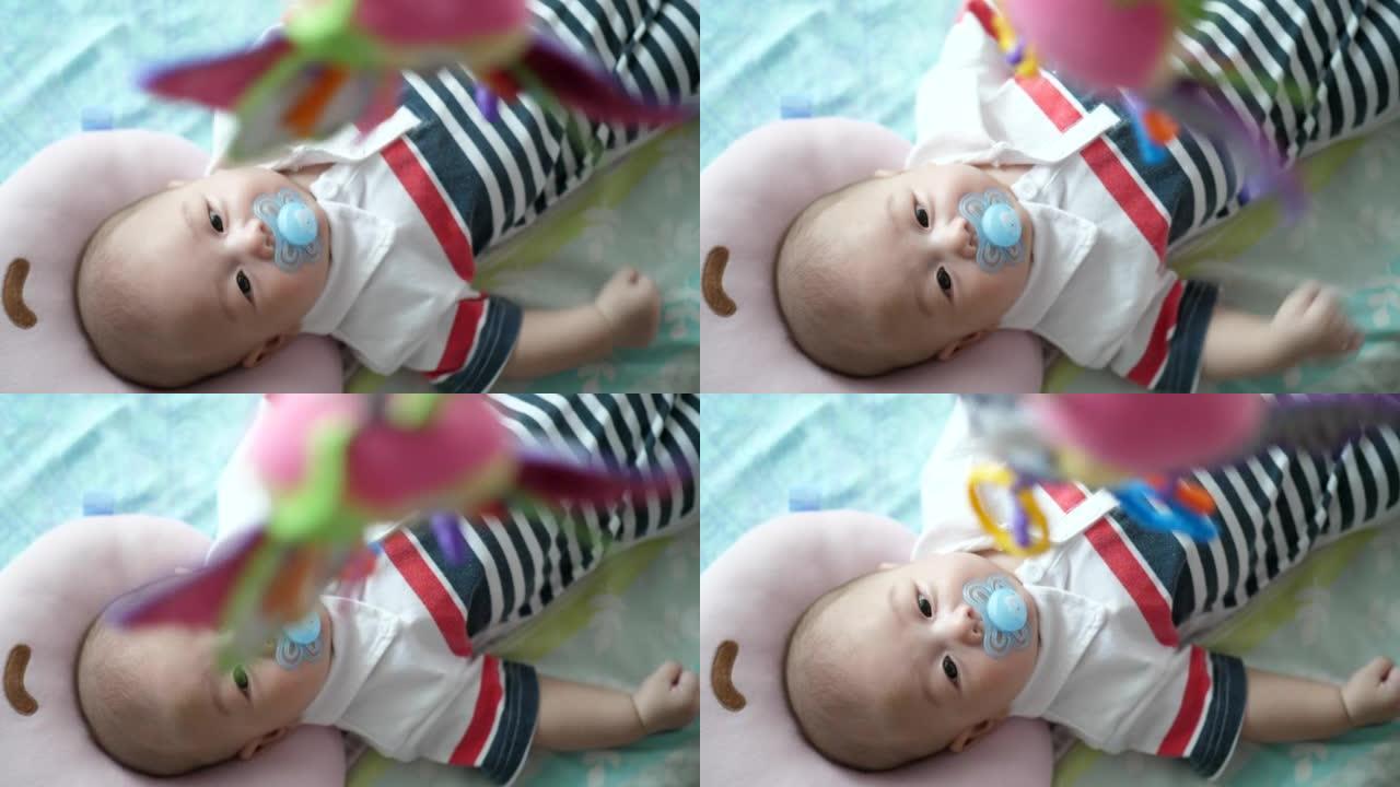 可爱的婴儿躺在婴儿床里看着悬挂的玩具