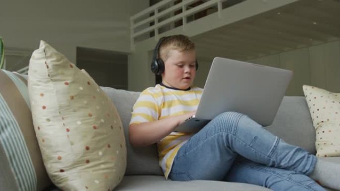白人男孩坐在客厅，独自在家使用笔记本电脑