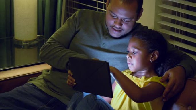 多种族女孩，父亲晚上看平板电脑