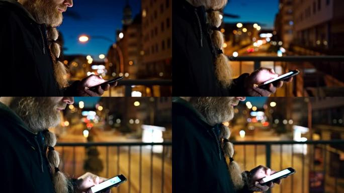 晚上在城市里散步时，无法辨认的留着长胡须的男子使用智能手机