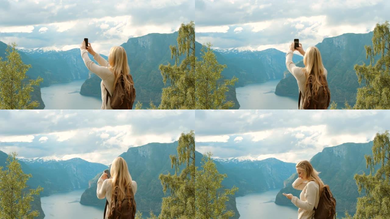 4k视频片段，一名年轻女子站着并用手机拍摄m ø reog Romsdal的照片