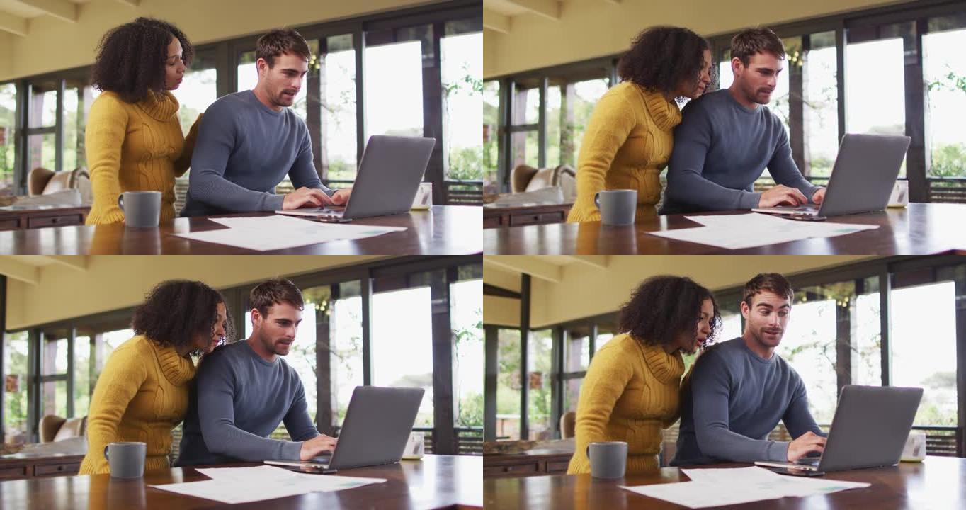 多样化的夫妇在客厅聊天，使用笔记本电脑，看文书工作和支付账单
