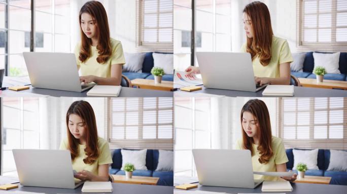 自由职业者亚洲女性休闲服的肖像，使用笔记本电脑在家里的客厅工作。