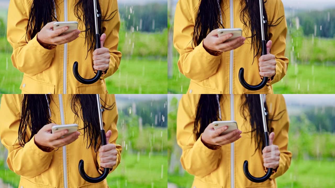 穿着雨衣的SLO MO无法识别的女人在雨中使用智能手机