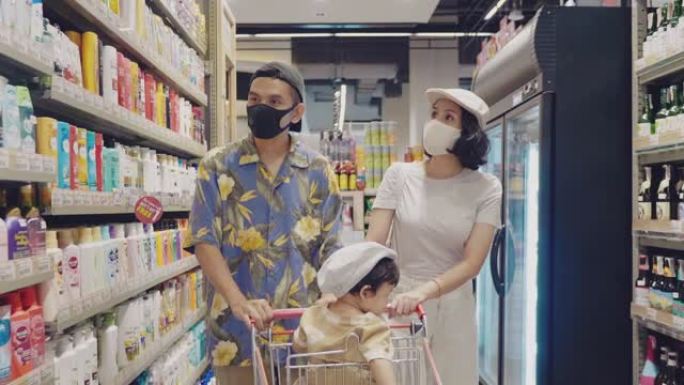 年轻的家庭带着戴着口罩的小女孩在超市购物
