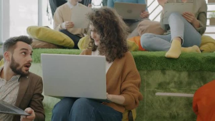 在现代舒适的办公空间中，缩小使用笔记本电脑并与同事交谈的女性员工的范围