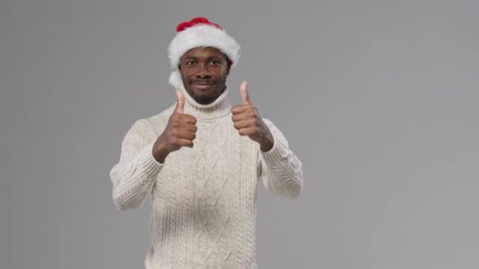 一个戴着圣诞帽和羊毛针织毛衣的黑皮肤男人微笑着指向他旁边的一个空白空间