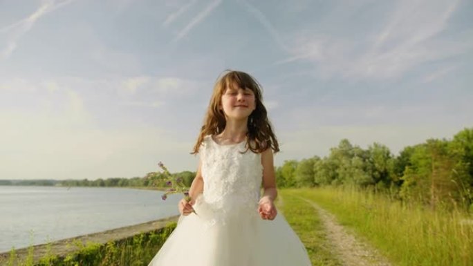 穿着白色连衣裙的SLO MO小女孩在河边散步