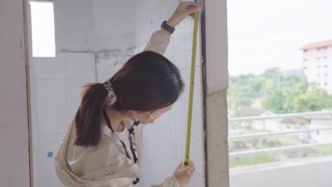 女土木工程师测量室内建筑墙壁的准确性。