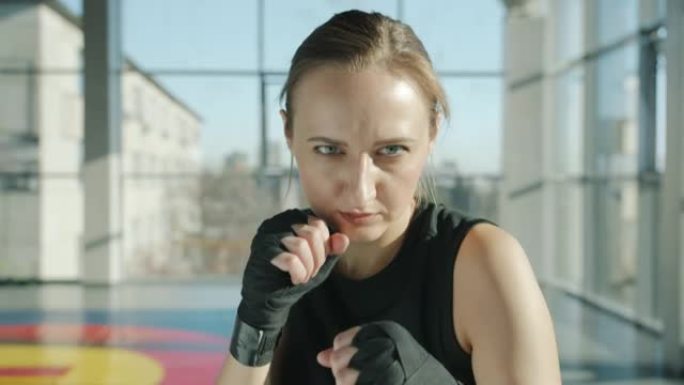专业女拳击手在健身房用包裹的手训练来进行打孔动作