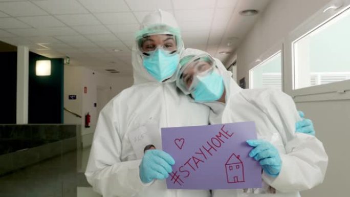 两名医疗保健一线工作人员在医院举着居家标志的肖像